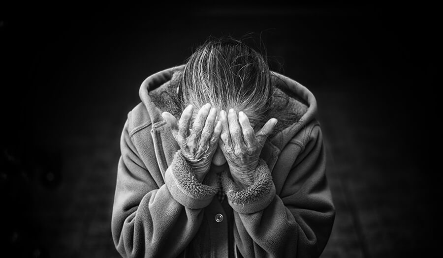 A black and white image of a lady with her head in her hands, bereaving a lost spouse.