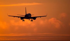 Image of a plane flying in a sunset for international repatriation cremated remains options with Rowland Brothers